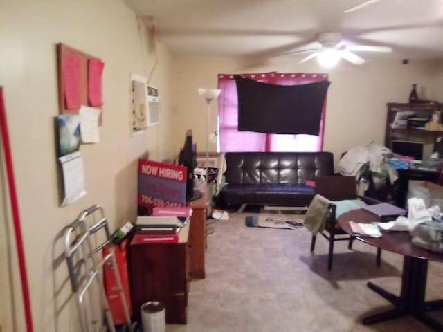 carpeted living room featuring ceiling fan and a wall mounted air conditioner