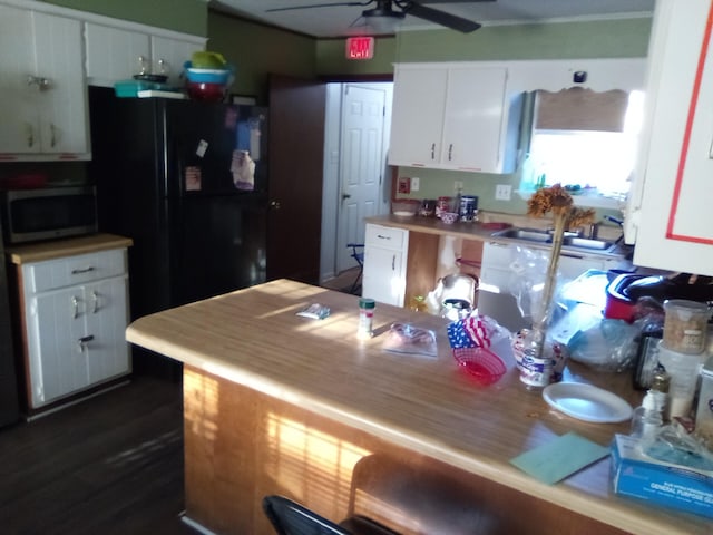 kitchen with black refrigerator, ceiling fan, sink, and white cabinetry