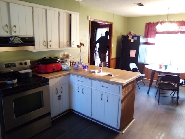 kitchen featuring exhaust hood, black fridge, white cabinets, and stainless steel electric range