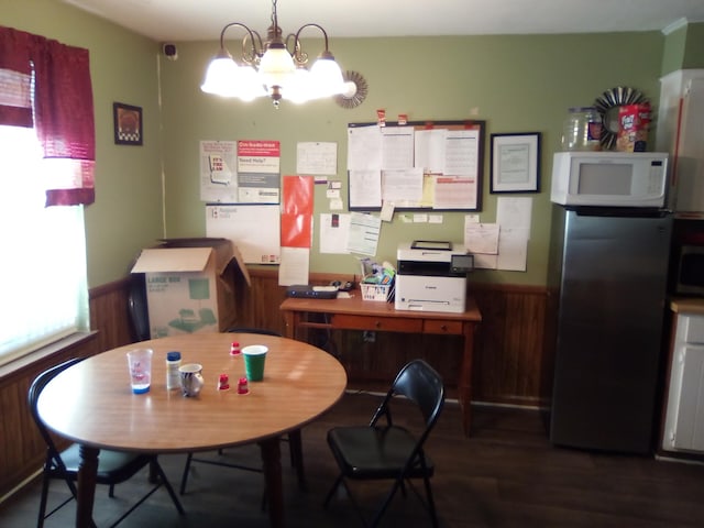 dining area with dark hardwood / wood-style flooring, wood walls, and a chandelier