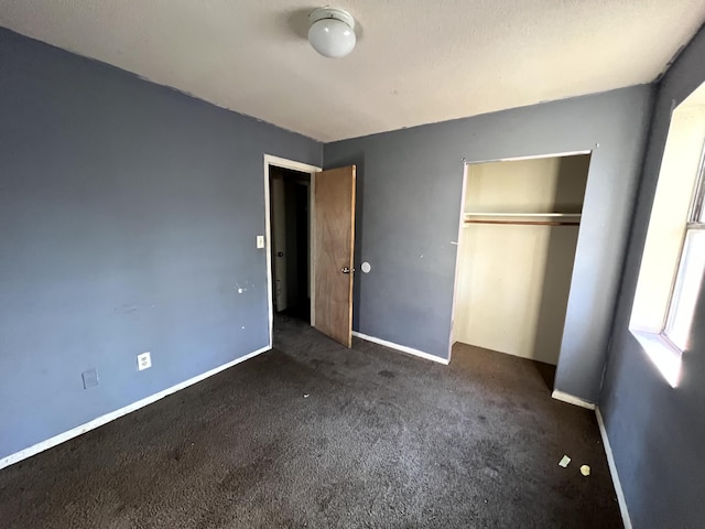 unfurnished bedroom with dark colored carpet and a closet