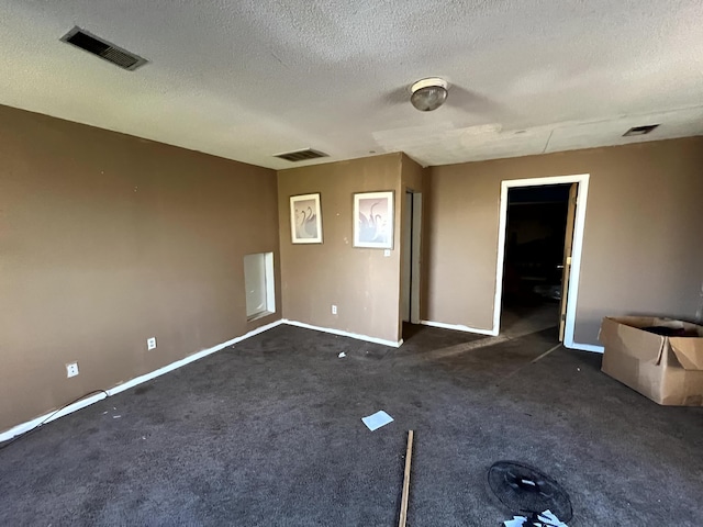 empty room with dark carpet and a textured ceiling