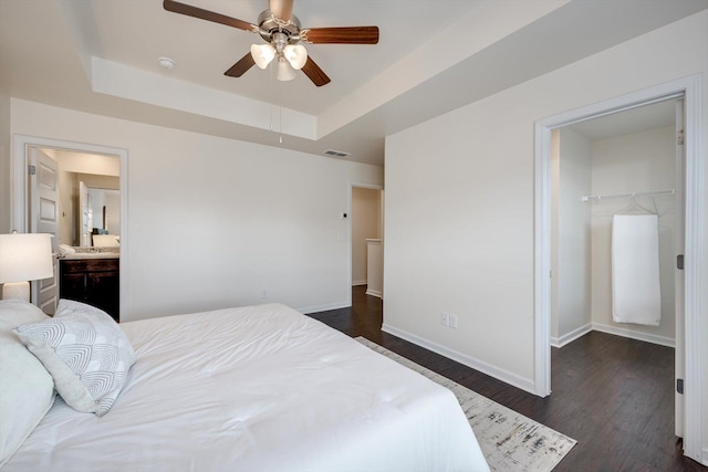 2178 River Park Ct, Augusta, GA 30907 - bedroom featuring a walk in closet, a tray ceiling, dark wood-style floors, a closet, and a ceiling fan