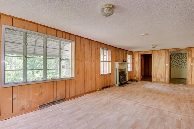 2514 Lumpkin Rd, Augusta, GA 30906 - unfurnished living room featuring light wood-style flooring, a textured ceiling, wooden walls, and visible vents