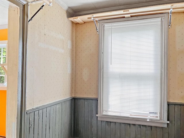 interior space with wallpapered walls, crown molding, and wainscoting