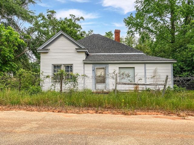 exterior space featuring a shingled roof, a chimney, and fence private yard