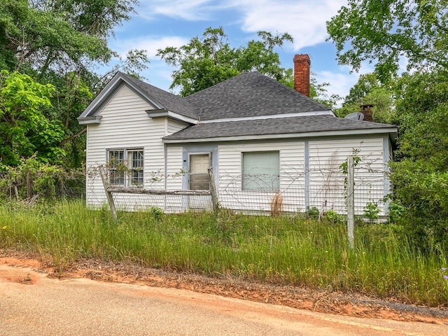 exterior space featuring a chimney and a shingled roof