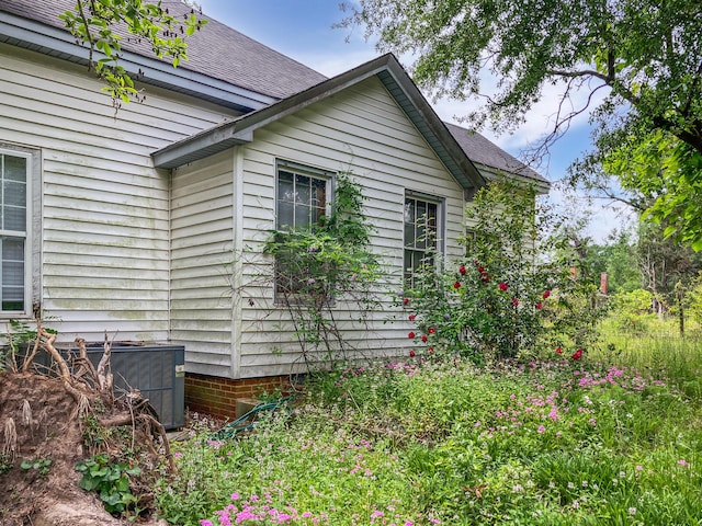 view of home's exterior with central air condition unit and a shingled roof