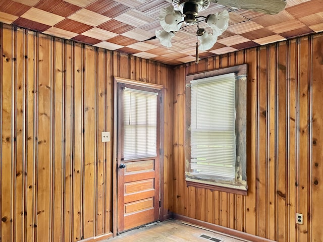 interior space featuring visible vents, a ceiling fan, wood walls, and a healthy amount of sunlight