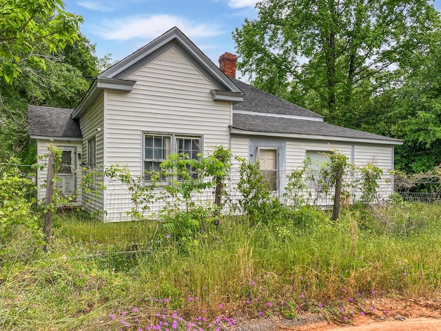 view of side of property with a chimney and a shingled roof