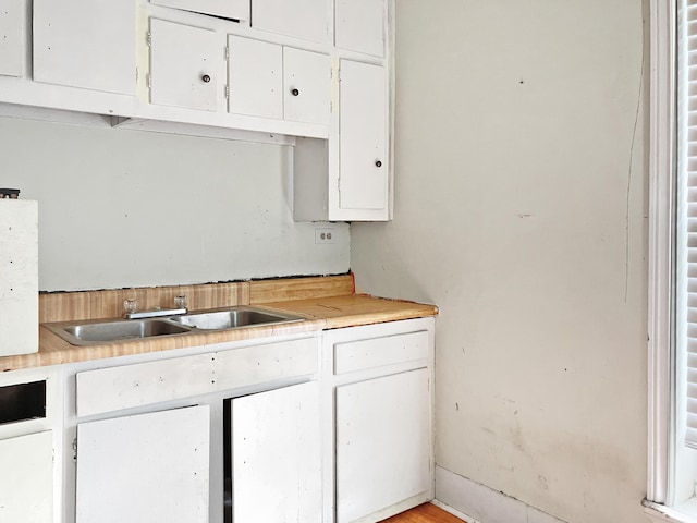 kitchen featuring white cabinets, a sink, and light countertops