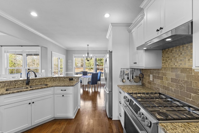 kitchen featuring appliances with stainless steel finishes, a sink, under cabinet range hood, white cabinetry, and a notable chandelier