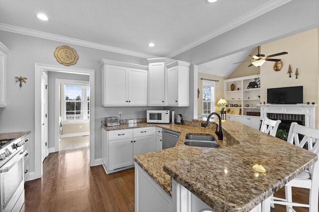 kitchen featuring range with gas cooktop, white microwave, a breakfast bar area, a peninsula, and a sink