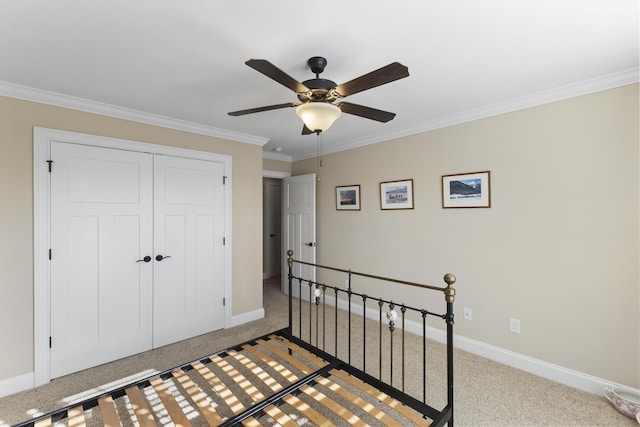 bedroom with baseboards, a ceiling fan, ornamental molding, carpet floors, and a closet