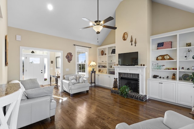 living room with built in features, ceiling fan, dark wood-style flooring, a brick fireplace, and high vaulted ceiling