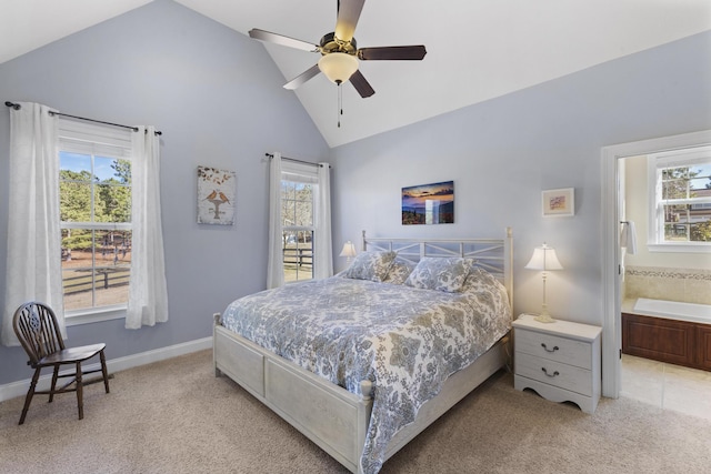 bedroom featuring ceiling fan, light colored carpet, baseboards, vaulted ceiling, and ensuite bath