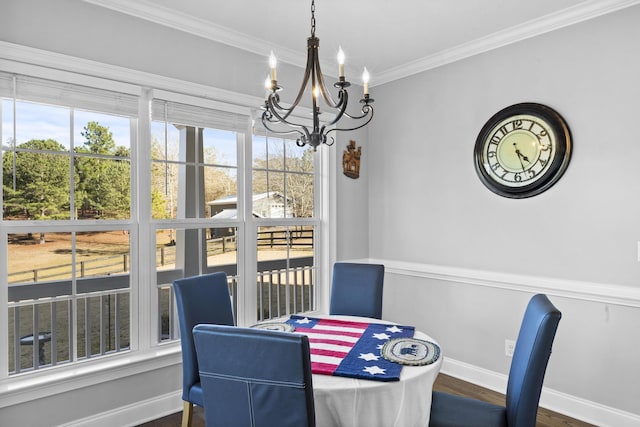 dining area with dark wood finished floors, a notable chandelier, crown molding, and baseboards