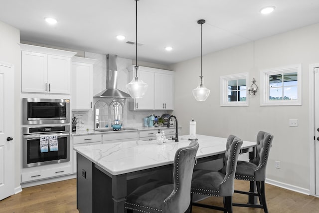 4136 Buffalo Trl, Evans, GA 30809 - kitchen featuring appliances with stainless steel finishes, decorative backsplash, a kitchen island with sink, wall chimney exhaust hood, and a breakfast bar
