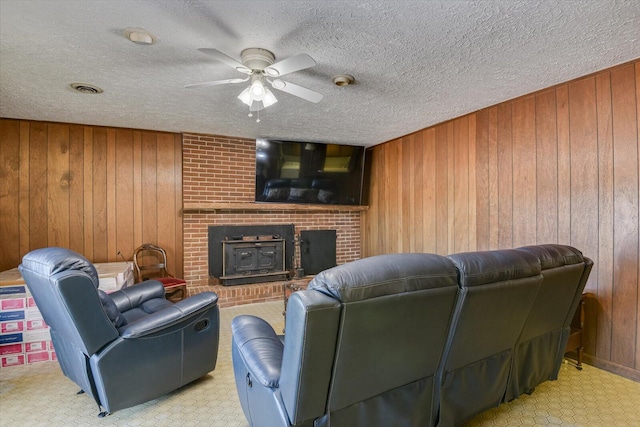 living room with ceiling fan, a wood stove, and wooden walls