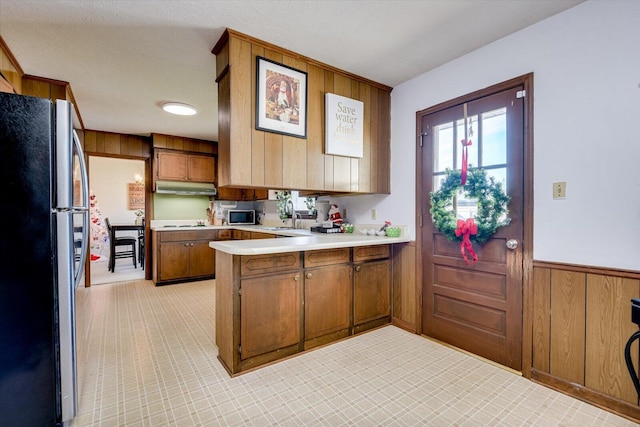 kitchen with wood walls, kitchen peninsula, sink, and appliances with stainless steel finishes