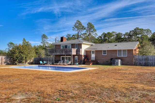 rear view of property featuring a lawn, a fenced in pool, and central air condition unit