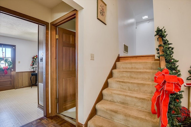 stairway featuring wood walls and parquet flooring