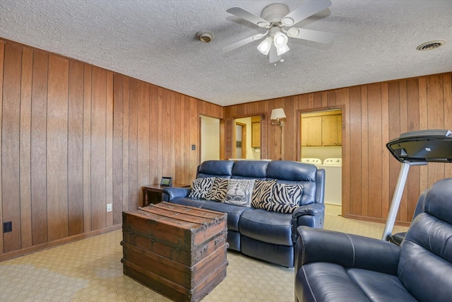 living room with wooden walls, ceiling fan, and washer and dryer