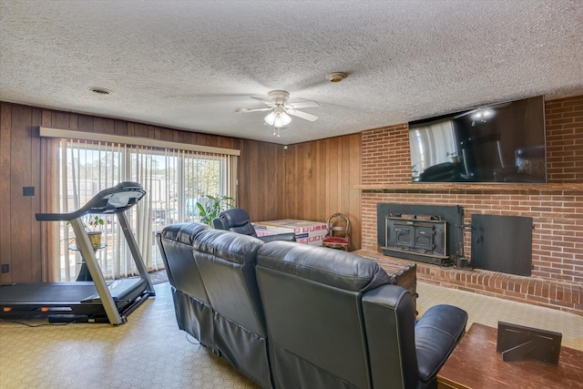 living room featuring ceiling fan, wood walls, and a textured ceiling