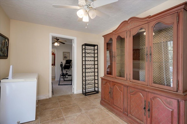 hall featuring a textured ceiling, light tile patterned flooring, and baseboards