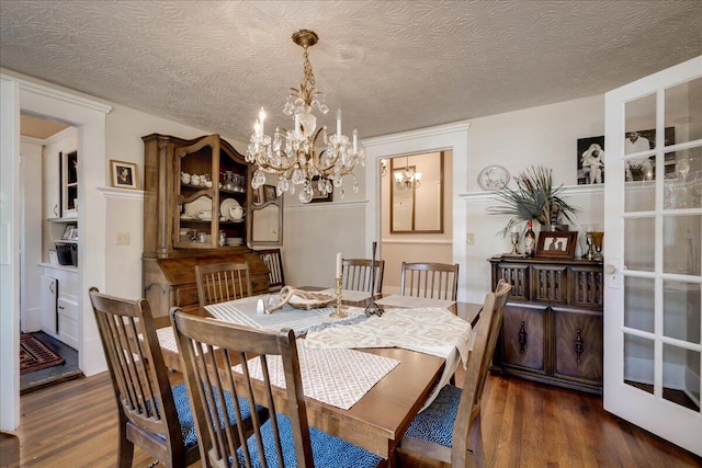 dining room with dark wood-style floors, a textured ceiling, and a notable chandelier