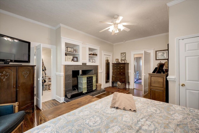 bedroom with dark wood-style floors, crown molding, a fireplace, and a textured ceiling