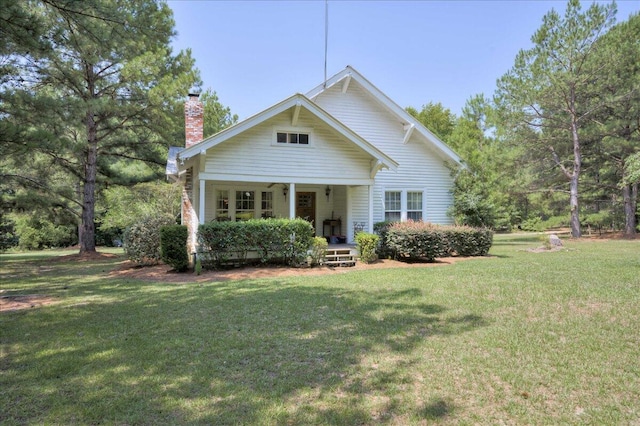 bungalow with covered porch, a chimney, and a front lawn