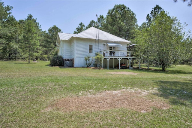 back of house with a deck, metal roof, and a lawn