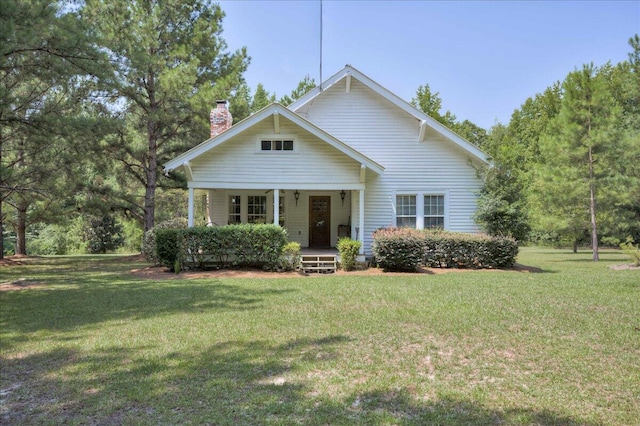 bungalow-style house with a porch, a chimney, and a front lawn