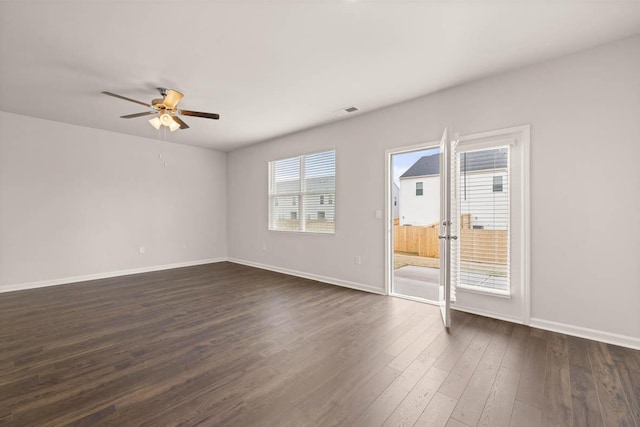 empty room with ceiling fan, dark wood-type flooring, and a wealth of natural light