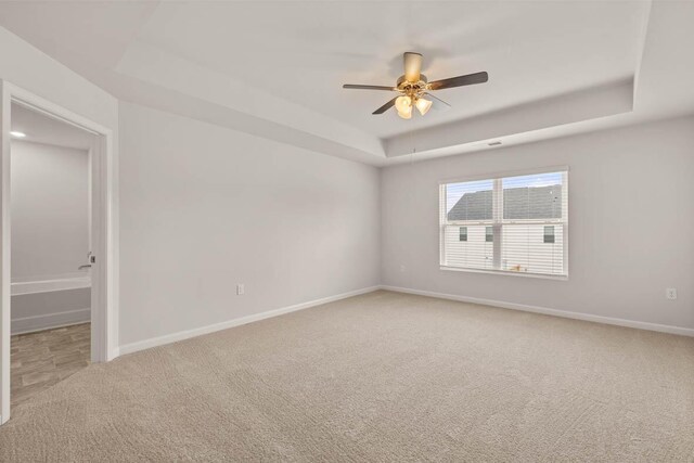 carpeted empty room featuring a raised ceiling and ceiling fan