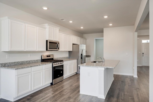 kitchen with white cabinetry, sink, light stone counters, an island with sink, and appliances with stainless steel finishes