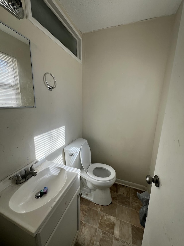 bathroom featuring toilet, vanity, and a healthy amount of sunlight