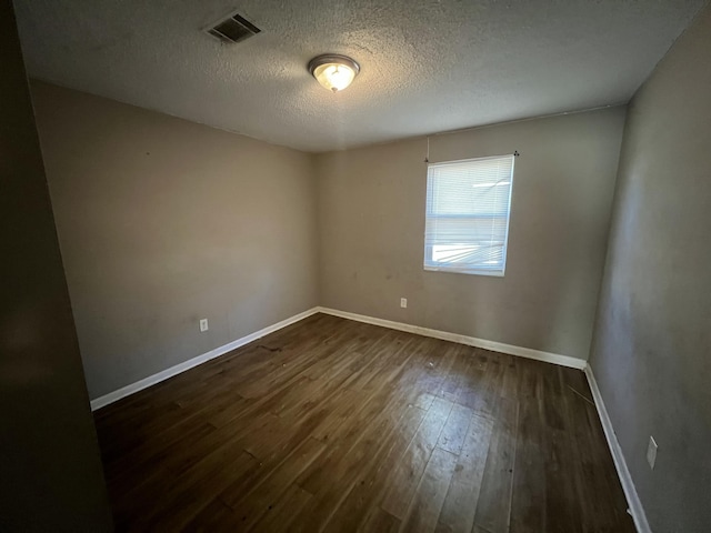 empty room featuring dark wood-type flooring and a textured ceiling