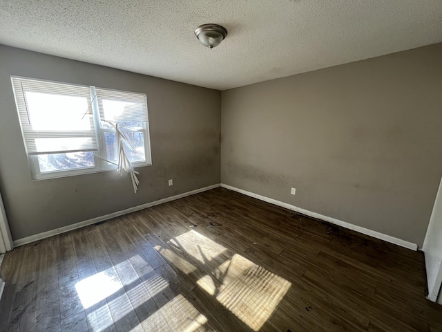 empty room with dark hardwood / wood-style flooring and a textured ceiling