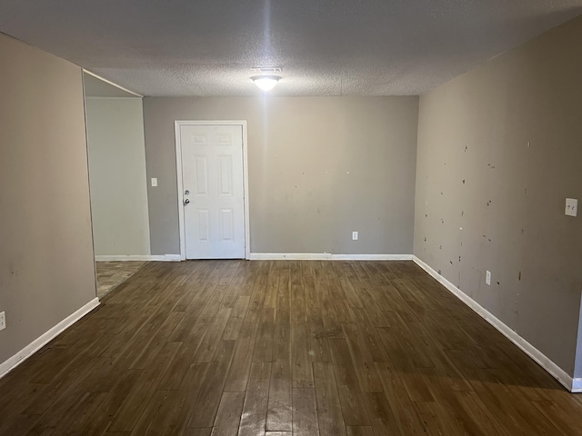 empty room featuring a textured ceiling and dark wood-type flooring