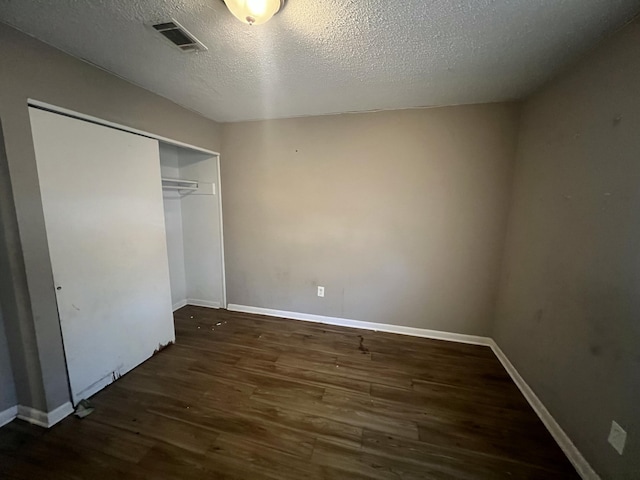 unfurnished bedroom with a textured ceiling, a closet, and dark hardwood / wood-style flooring