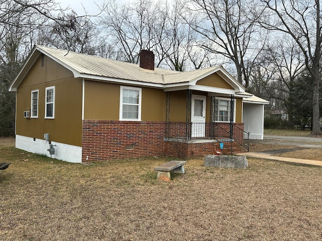 view of front of property featuring crawl space, a chimney, metal roof, and brick siding