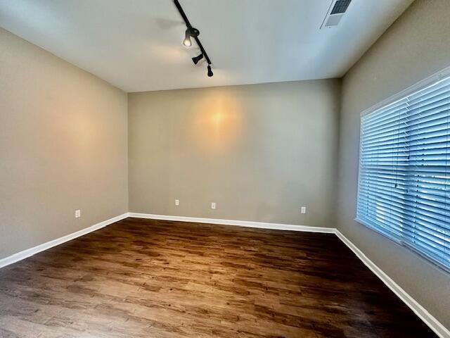 empty room featuring hardwood / wood-style flooring and track lighting