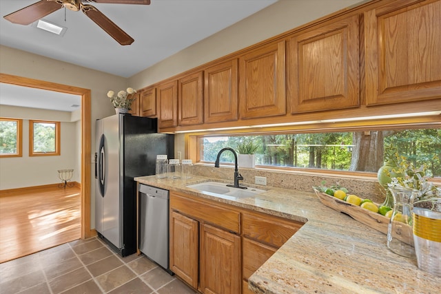 kitchen featuring light stone countertops, appliances with stainless steel finishes, ceiling fan, sink, and tile patterned flooring