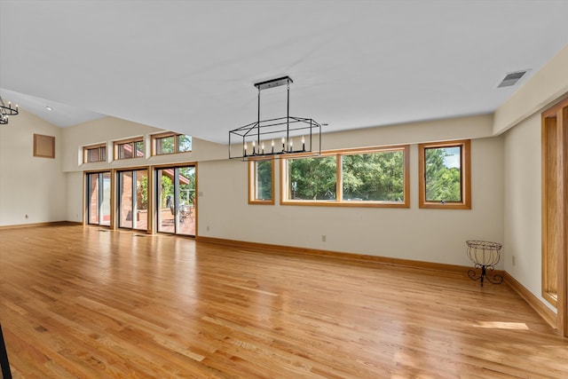 unfurnished living room featuring lofted ceiling, light hardwood / wood-style flooring, and a chandelier