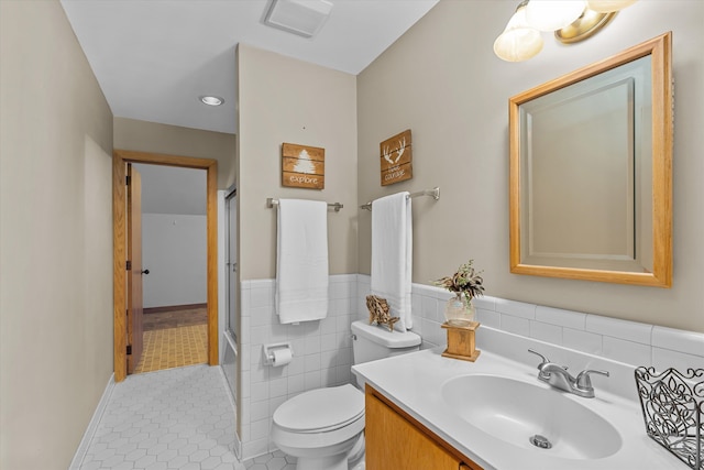 full bathroom with combined bath / shower with glass door, vanity, tile walls, tile patterned flooring, and toilet