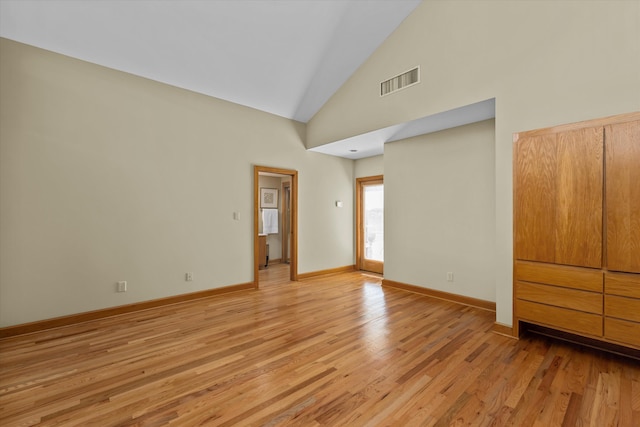 spare room with light hardwood / wood-style floors and high vaulted ceiling