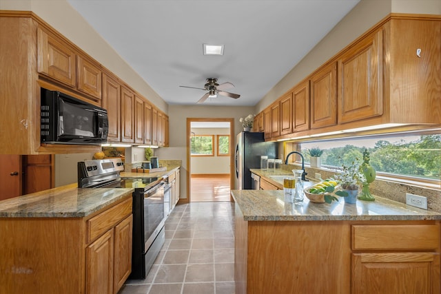 kitchen featuring light stone countertops, sink, ceiling fan, stainless steel appliances, and kitchen peninsula