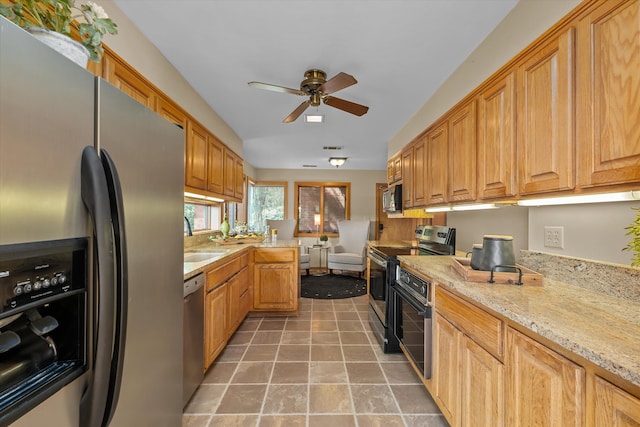 kitchen featuring light stone countertops, stainless steel appliances, ceiling fan, and sink